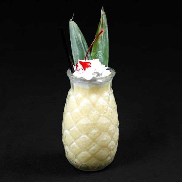 Perico Ripiao's pineapple-shaped glass filled with a creamy drink, topped with whipped cream, a cherry, and leaves.