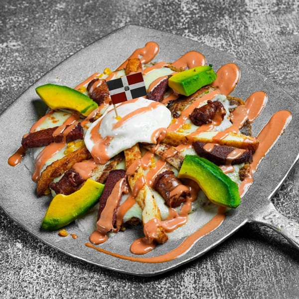 Dominican dish with fried cheese, sausage, avocado, and sauce, topped with a Dominican flag pick.